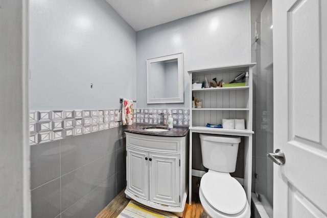 bathroom with hardwood / wood-style flooring, vanity, toilet, and tile walls