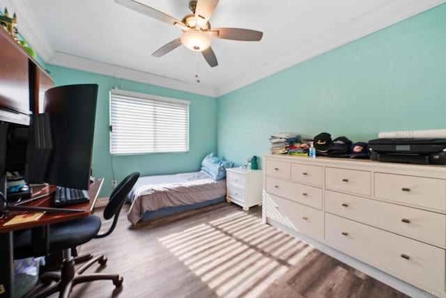 bedroom featuring hardwood / wood-style floors, ornamental molding, and ceiling fan