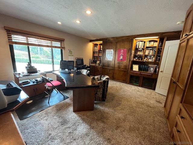 carpeted home office featuring a textured ceiling