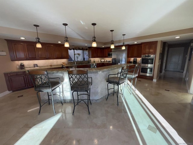 kitchen featuring a spacious island, a kitchen bar, hanging light fixtures, dark stone countertops, and stainless steel appliances