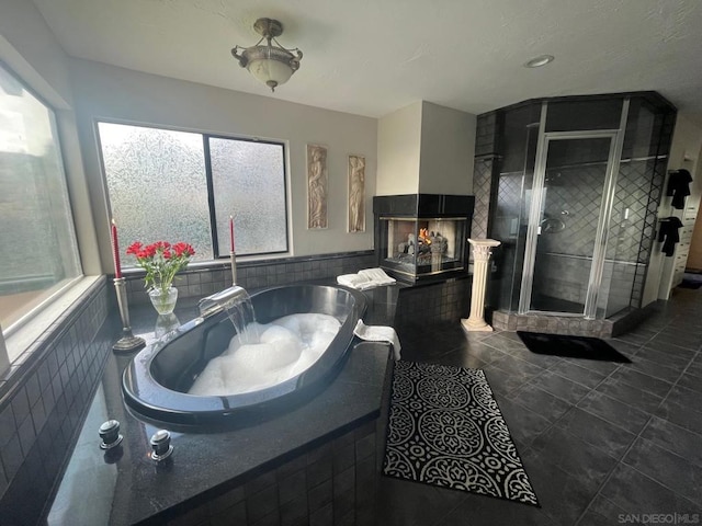 bathroom with tile patterned floors, separate shower and tub, and a multi sided fireplace