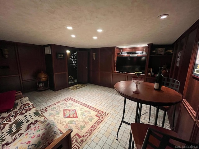 interior space featuring light tile patterned flooring, a textured ceiling, and wood walls