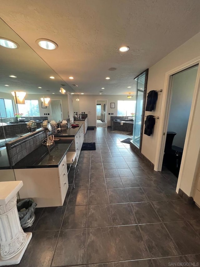 interior space with dark tile patterned floors, white cabinets, and a textured ceiling