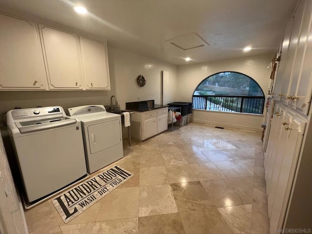 clothes washing area featuring cabinets and separate washer and dryer