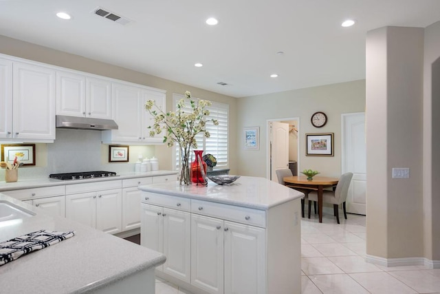 kitchen featuring a center island, stainless steel gas cooktop, light tile patterned floors, and white cabinets