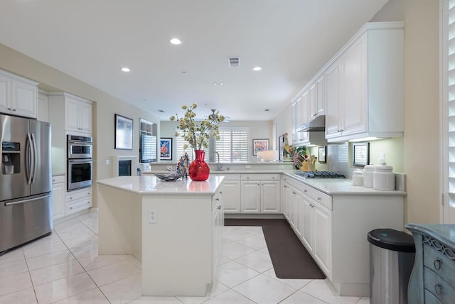 kitchen featuring white cabinetry, appliances with stainless steel finishes, a kitchen island, and light tile patterned floors