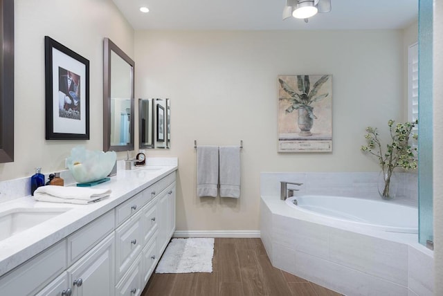 bathroom with vanity, hardwood / wood-style flooring, and tiled bath