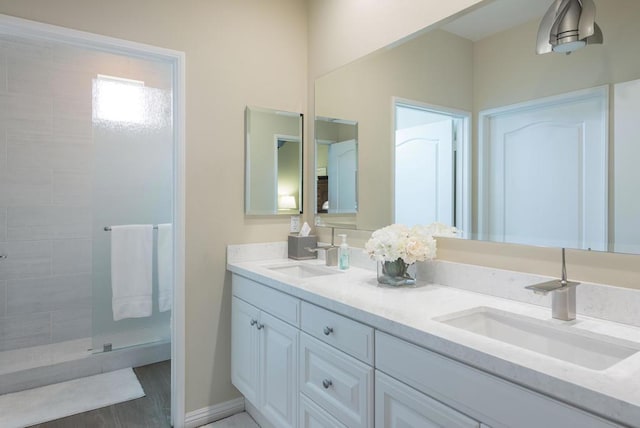 bathroom with tiled shower, vanity, and wood-type flooring