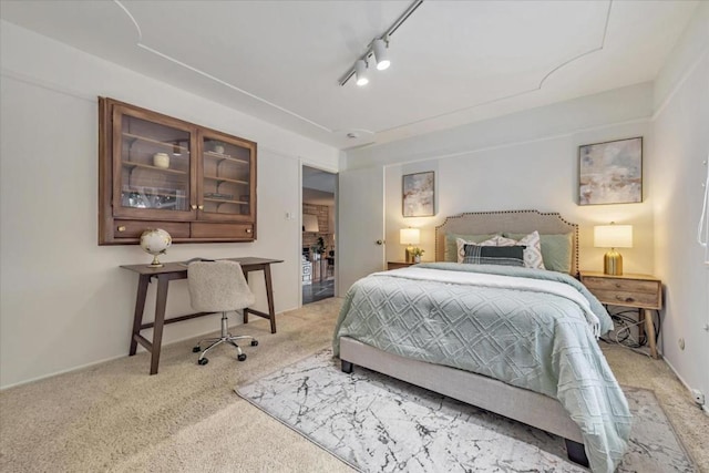 bedroom featuring track lighting and light colored carpet