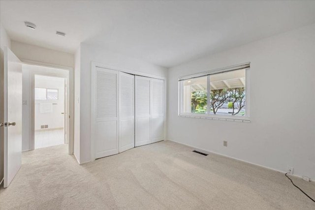 unfurnished bedroom featuring light colored carpet and a closet