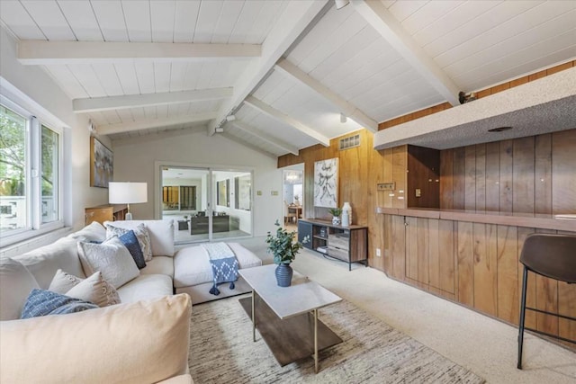 carpeted living room with lofted ceiling with beams and wooden walls