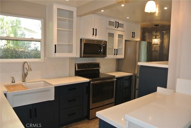 kitchen featuring appliances with stainless steel finishes, sink, white cabinets, and decorative light fixtures