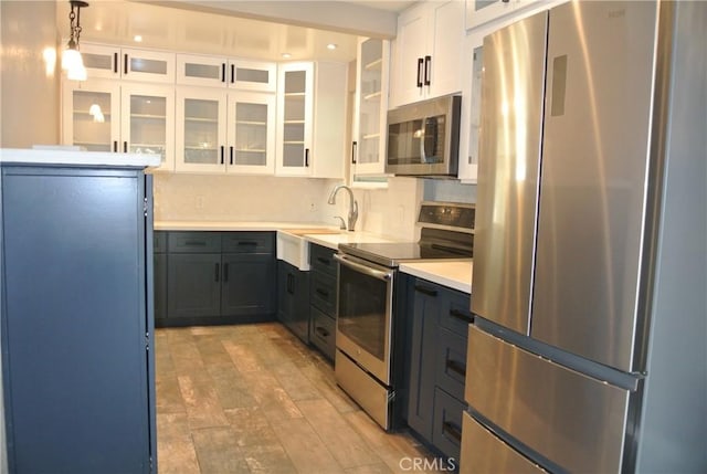 kitchen with sink, white cabinetry, hanging light fixtures, backsplash, and stainless steel appliances