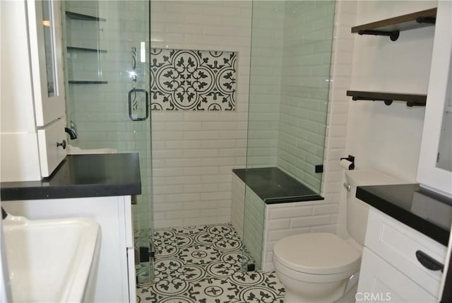 bathroom with tile patterned floors, vanity, toilet, and a shower with shower door