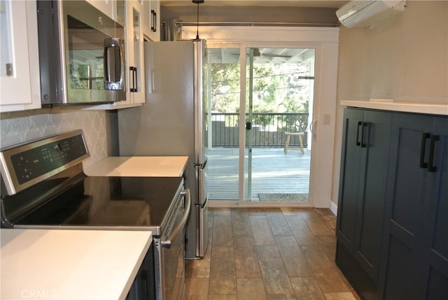 kitchen with appliances with stainless steel finishes, hardwood / wood-style floors, a wall mounted air conditioner, backsplash, and hanging light fixtures