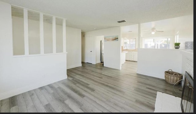 empty room featuring ceiling fan, light hardwood / wood-style floors, and a textured ceiling