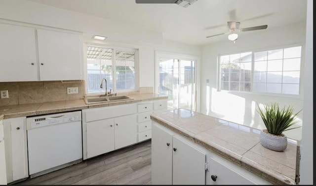 kitchen with sink, white cabinetry, tile countertops, white dishwasher, and backsplash