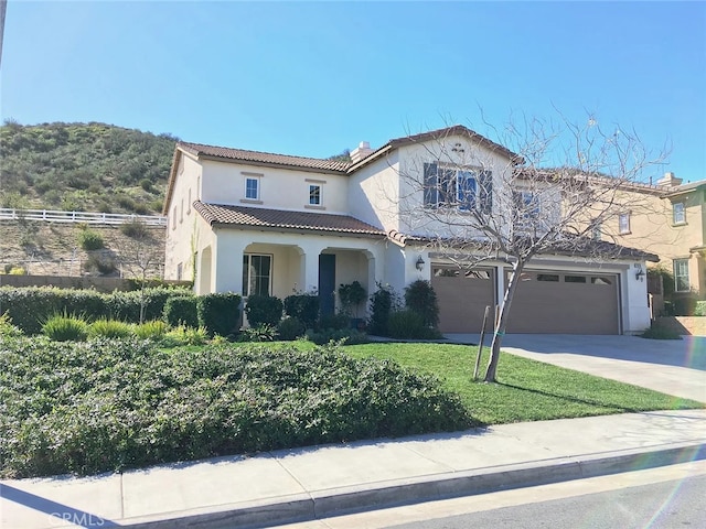 mediterranean / spanish-style house featuring a garage and a front lawn