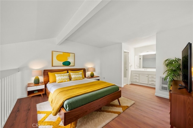 bedroom with connected bathroom, vaulted ceiling with beams, wood-type flooring, and heating unit