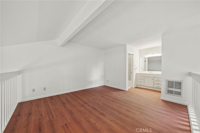 additional living space featuring vaulted ceiling with beams and wood-type flooring