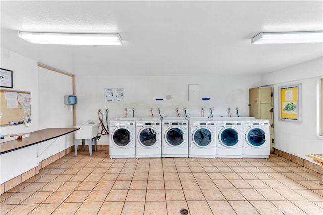 laundry room with washing machine and clothes dryer, sink, and light tile patterned floors