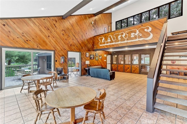 tiled dining space featuring beamed ceiling, a towering ceiling, and a healthy amount of sunlight