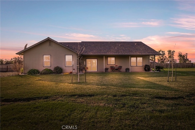 back house at dusk with a lawn