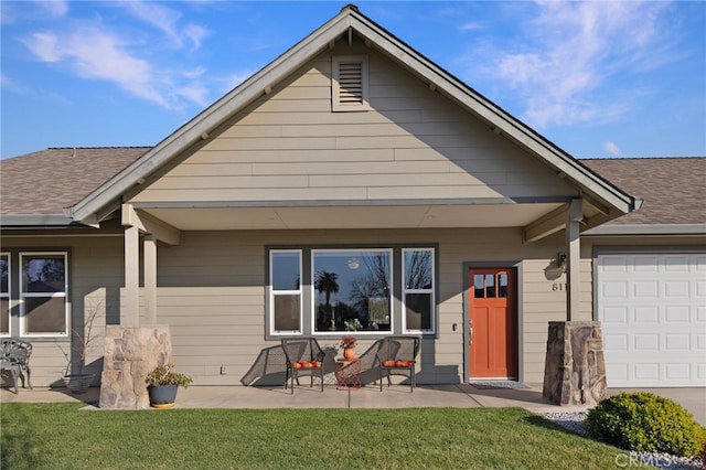 rear view of property featuring a garage, a lawn, and covered porch