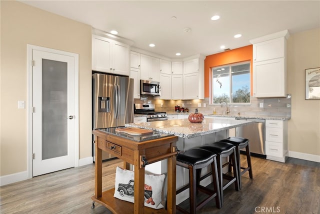 kitchen with backsplash, light stone countertops, white cabinets, and appliances with stainless steel finishes