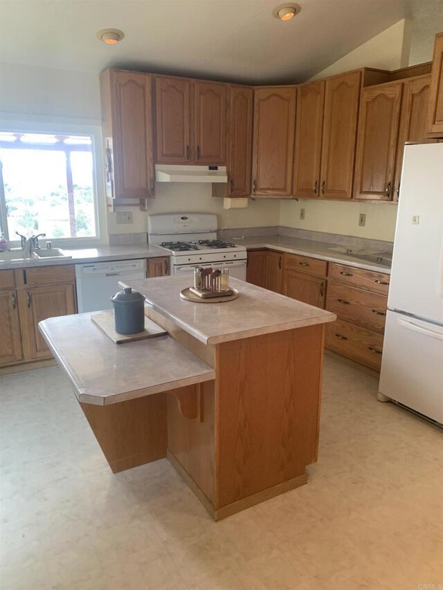 kitchen with vaulted ceiling, white appliances, sink, and a kitchen island