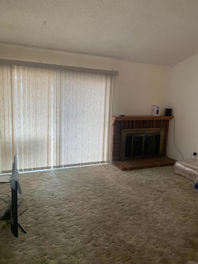 unfurnished living room featuring carpet floors, a textured ceiling, and a fireplace