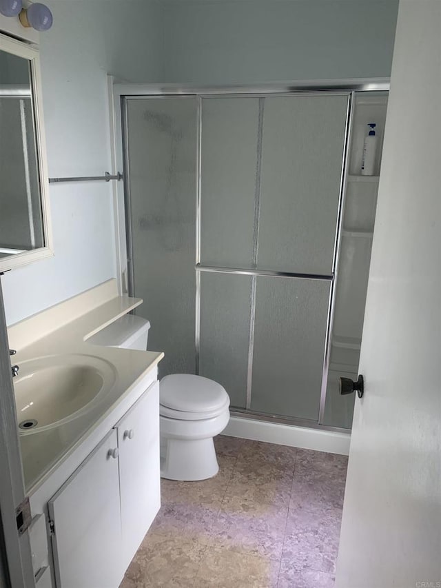 bathroom featuring vanity, a shower with door, and toilet