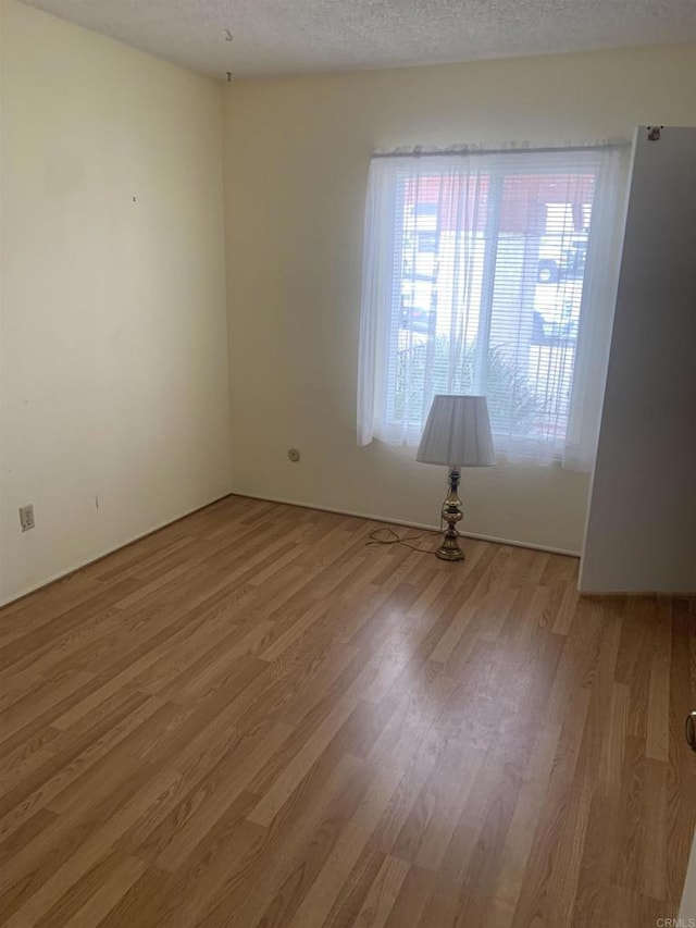 spare room with a textured ceiling and light hardwood / wood-style floors