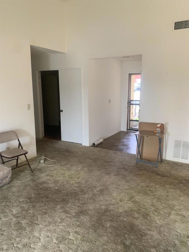 carpeted spare room featuring a high ceiling