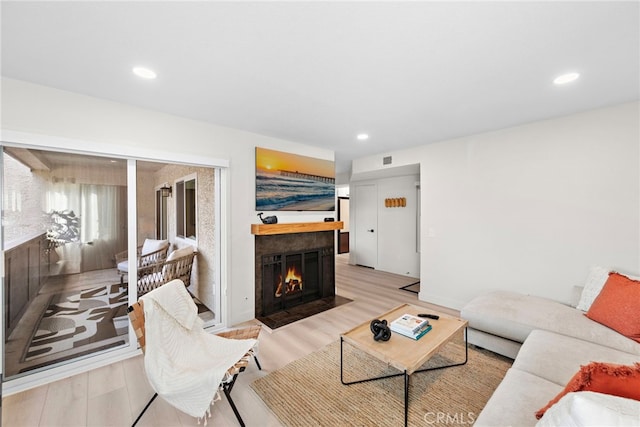 living area with light wood finished floors, a fireplace with flush hearth, visible vents, and recessed lighting