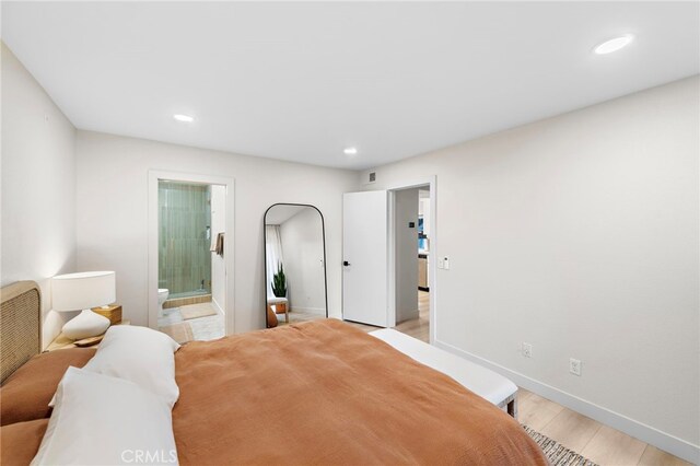 bedroom with ensuite bath and light hardwood / wood-style flooring