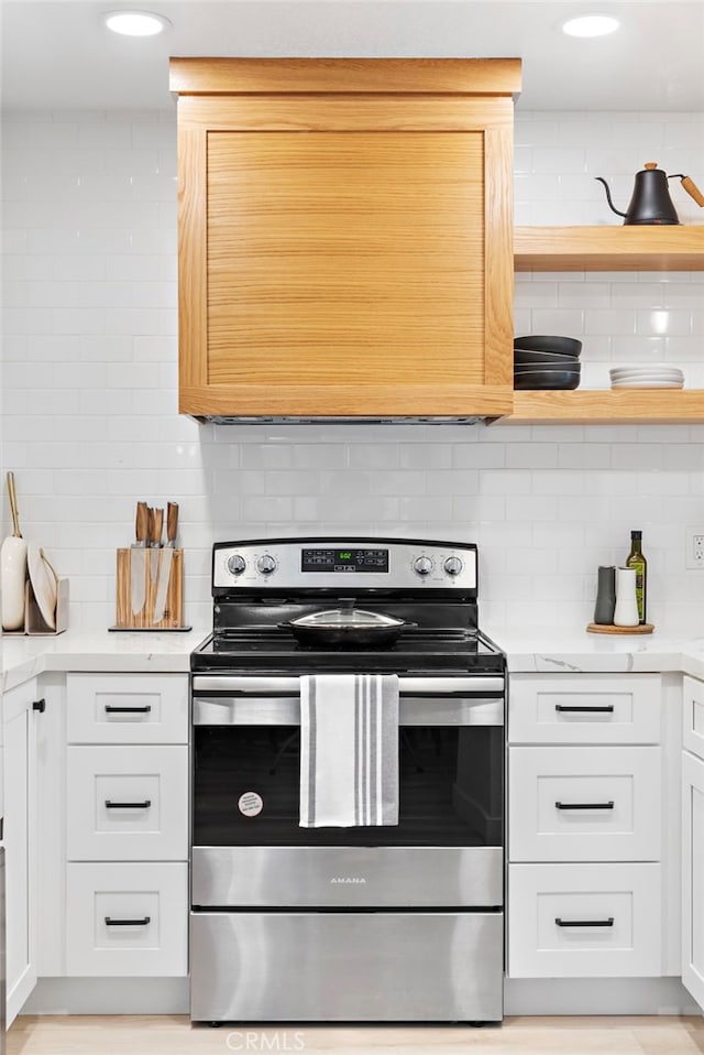 kitchen featuring open shelves, decorative backsplash, white cabinetry, light stone countertops, and stainless steel range with electric stovetop