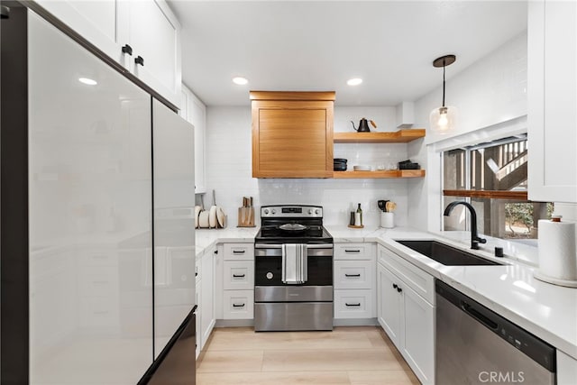 kitchen featuring white cabinetry, sink, stainless steel appliances, and hanging light fixtures