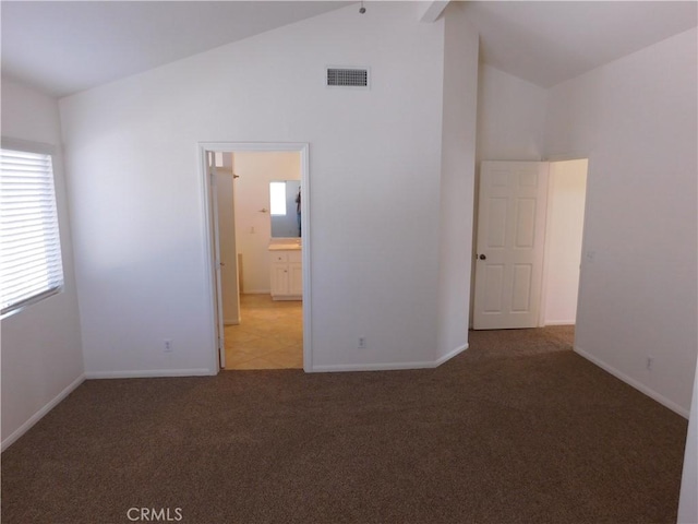 unfurnished bedroom featuring connected bathroom, high vaulted ceiling, and carpet