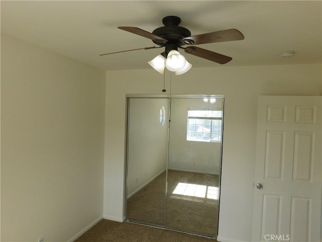 unfurnished bedroom with dark carpet, a closet, and ceiling fan