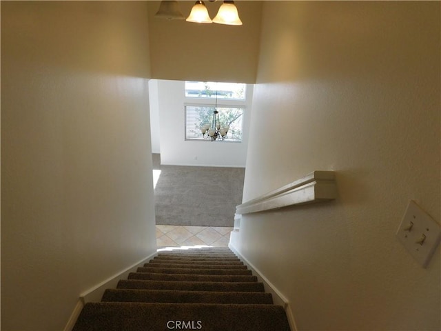 stairs featuring a chandelier and carpet flooring