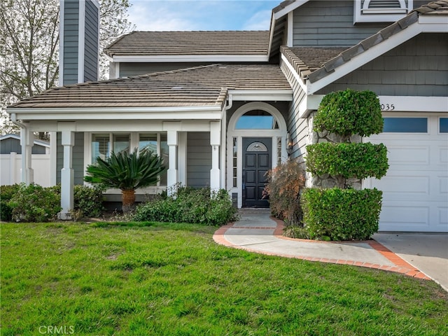 doorway to property with a garage, a tiled roof, and a yard