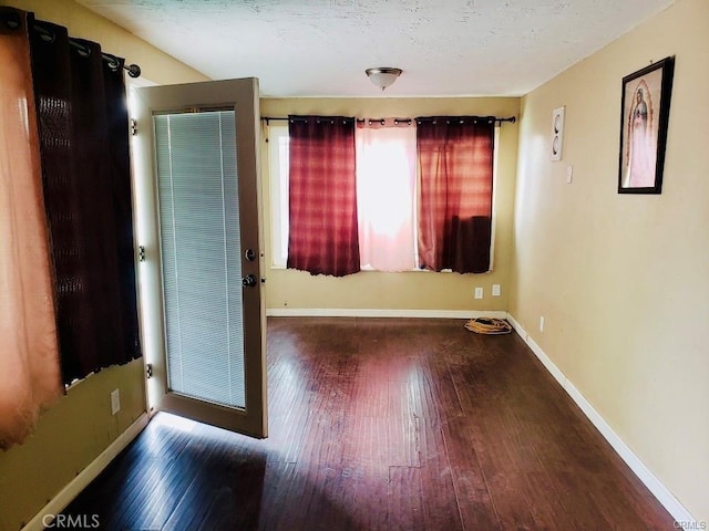 spare room with dark hardwood / wood-style floors and a textured ceiling