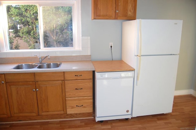 kitchen featuring sink, white appliances, and light hardwood / wood-style flooring