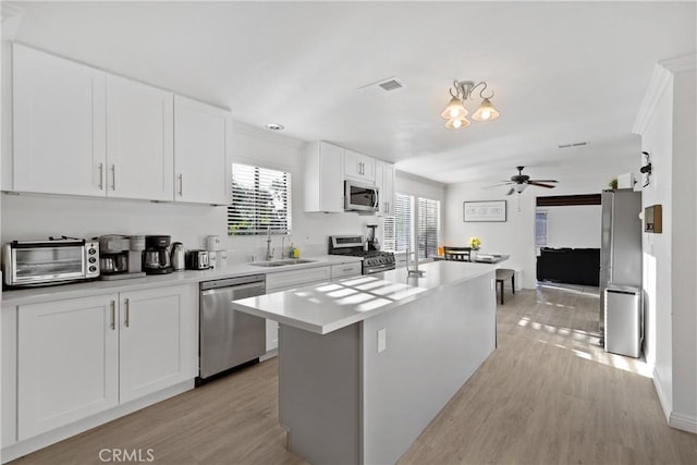 kitchen featuring sink, a center island, ceiling fan, stainless steel appliances, and white cabinets