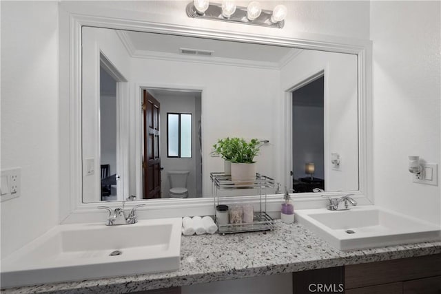 bathroom with crown molding, vanity, and toilet