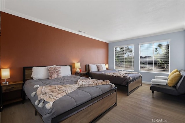 bedroom with ornamental molding and light wood-type flooring