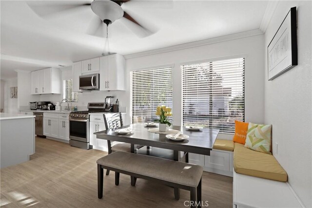 dining room with crown molding, sink, ceiling fan, and light wood-type flooring