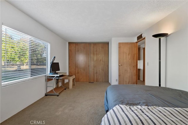 carpeted bedroom with a textured ceiling and a closet