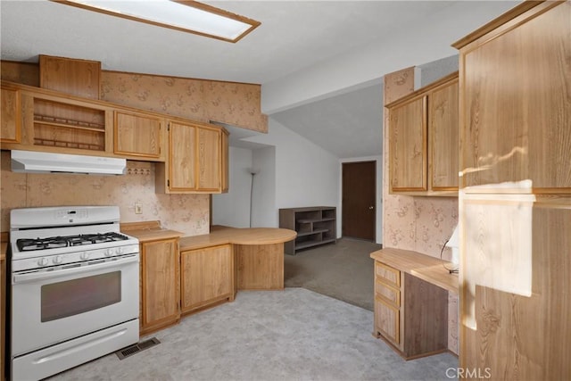 kitchen featuring vaulted ceiling, light brown cabinetry, white gas stove, and light carpet